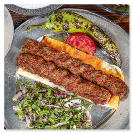 Adana kebab served over flatbread with grilled tomato